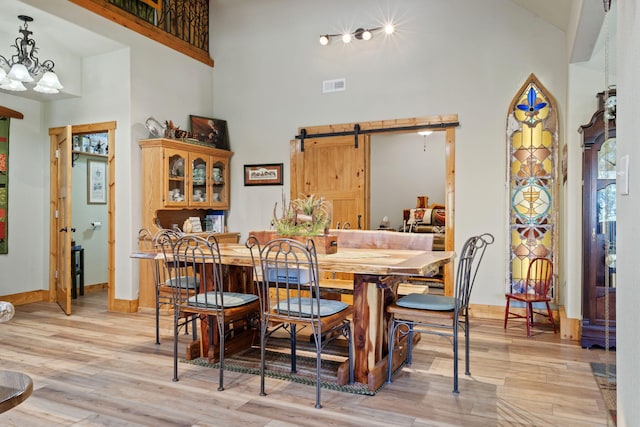 26474 Kings River Rd, Shell Knob, MO 65747 - dining space with a barn door, a high ceiling, light wood-style flooring, and a chandelier