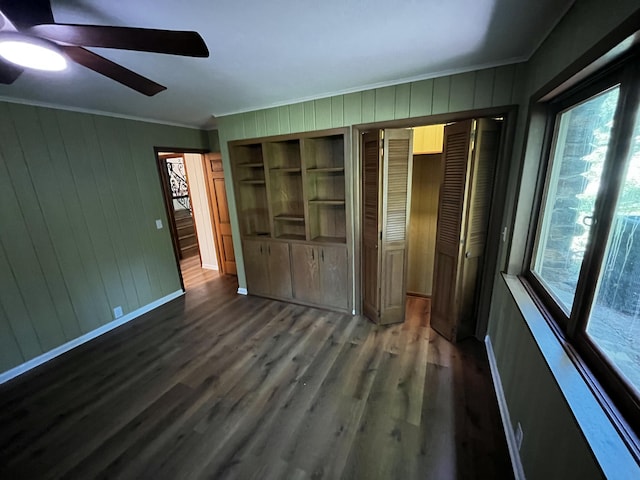 805 E 13th St, Cassville, MO 65625 - unfurnished bedroom with ornamental molding, wood finished floors, ceiling fan, multiple closets, and wooden walls