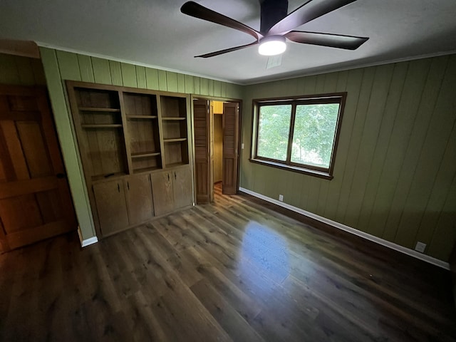 805 E 13th St, Cassville, MO 65625 - unfurnished bedroom featuring ornamental molding, wooden walls, dark wood-type flooring, and ceiling fan