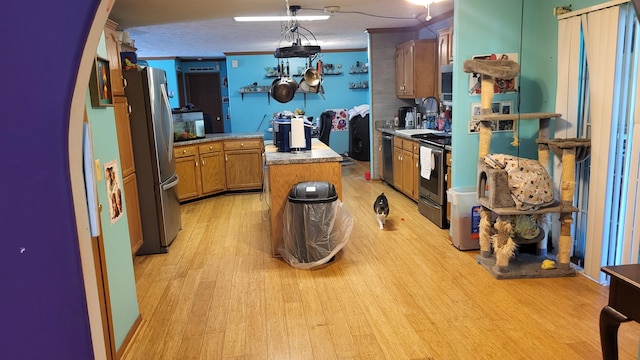 210 Castle Rock Dr, Kissee Mills, MO 65680 - kitchen with appliances with stainless steel finishes, light wood finished floors, light countertops, brown cabinetry, and a kitchen island