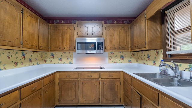 619 9th St, Thayer, MO 65791 - kitchen with stainless steel microwave, black electric stovetop, light countertops, wallpapered walls, and brown cabinets