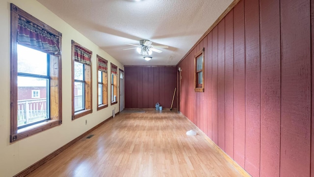619 9th St, Thayer, MO 65791 - unfurnished room featuring light wood finished floors, a ceiling fan, wood walls, and a textured ceiling