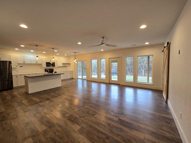 24136 Lazy Daze Ln, Wheatland, MO 65779 - unfurnished living room featuring recessed lighting, plenty of natural light, dark wood finished floors, and a barn door