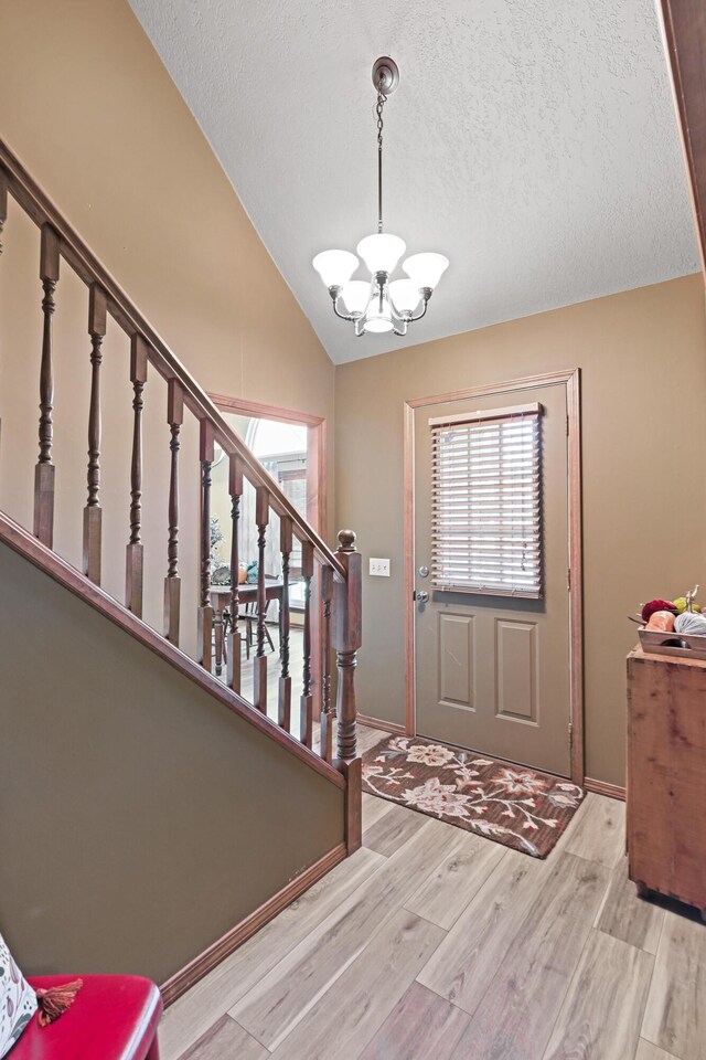1617 Alexandra Dr, Carthage, MO 64836 - foyer entrance with a chandelier, stairs, lofted ceiling, light wood-style floors, and a textured ceiling