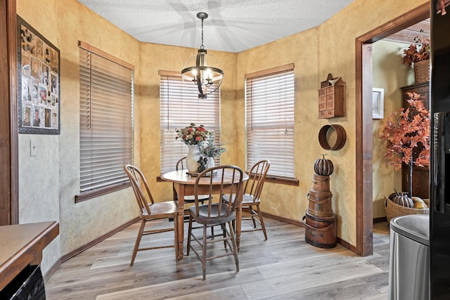 1617 Alexandra Dr, Carthage, MO 64836 - dining space with a chandelier, light wood-type flooring, a textured wall, and a textured ceiling
