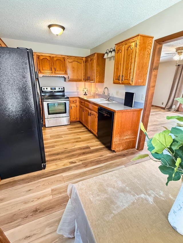 1617 Alexandra Dr, Carthage, MO 64836 - kitchen with black appliances, light countertops, a textured ceiling, light wood-type flooring, and brown cabinets