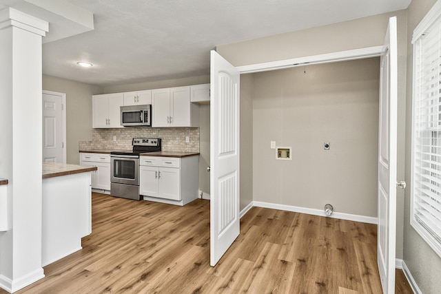 3539 S Walnut Hill Dr, Springfield, MO 65807 - kitchen with stainless steel appliances, white cabinetry, light wood finished floors, and backsplash