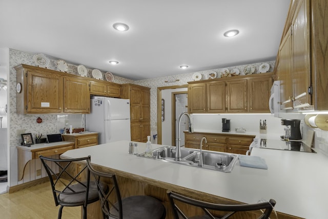 3416 S Barnes Ave, Springfield, MO 65804 - kitchen featuring wallpapered walls, white appliances, a peninsula, light countertops, and a breakfast bar