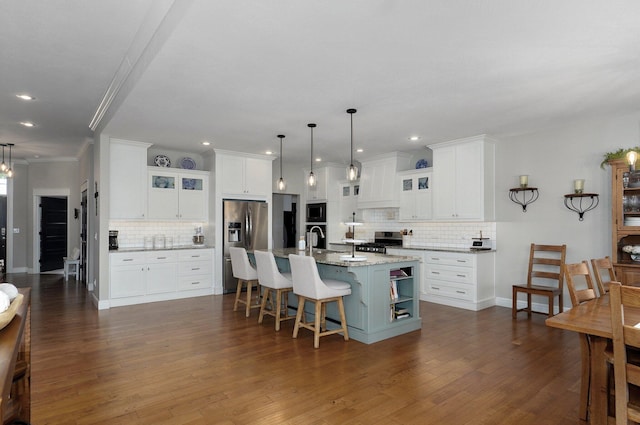 914 W Lorenza Dr, Nixa, MO 65714 - kitchen featuring appliances with stainless steel finishes, backsplash, a breakfast bar area, a center island with sink, and dark wood finished floors