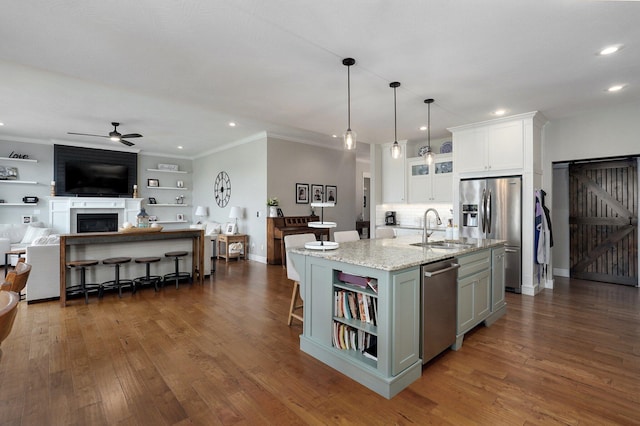 914 W Lorenza Dr, Nixa, MO 65714 - kitchen featuring appliances with stainless steel finishes, ceiling fan, open floor plan, white cabinetry, and a fireplace