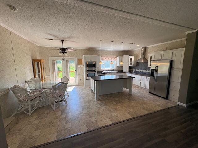 64 Inman Dr, Theodosia, MO 65761 - kitchen with stainless steel appliances, dark countertops, wall chimney range hood, a kitchen island, and white cabinets