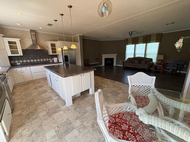 64 Inman Dr, Theodosia, MO 65761 - kitchen featuring wall chimney range hood, stainless steel fridge, dark countertops, a ceiling fan, and glass insert cabinets