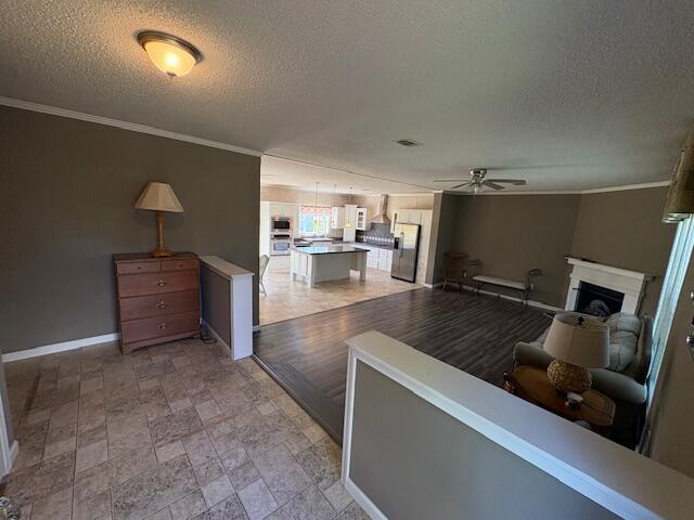 64 Inman Dr, Theodosia, MO 65761 - living room featuring ceiling fan, a textured ceiling, a fireplace, and ornamental molding