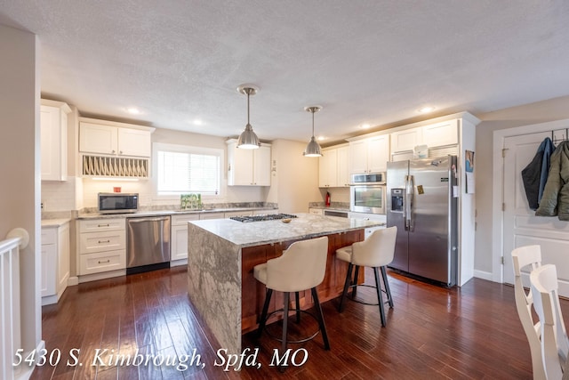 5430 S Kimbrough Ave, Springfield, MO 65810 - kitchen with stainless steel appliances, light stone countertops, a center island, dark wood finished floors, and white cabinets