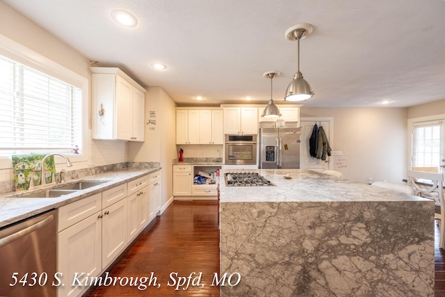 5430 S Kimbrough Ave, Springfield, MO 65810 - kitchen featuring appliances with stainless steel finishes, dark wood-style flooring, light stone counters, white cabinetry, and hanging light fixtures