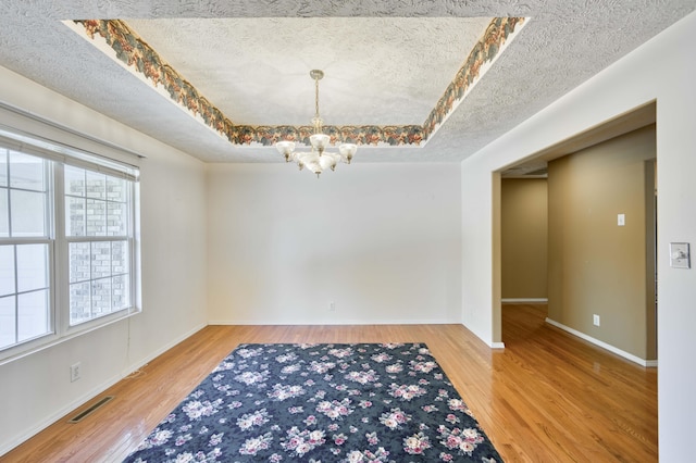 784 S 17th St, Ozark, MO 65721 - empty room featuring a textured ceiling, a chandelier, healthy amount of natural light, wood finished floors, and a raised ceiling
