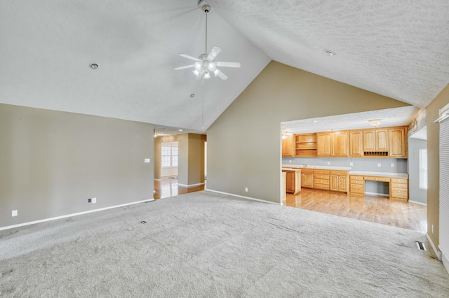 784 S 17th St, Ozark, MO 65721 - unfurnished living room with high vaulted ceiling, light colored carpet, a ceiling fan, built in study area, and a textured ceiling