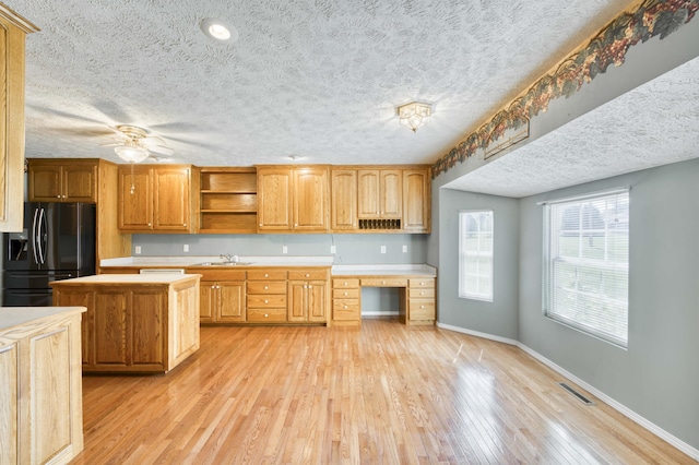 784 S 17th St, Ozark, MO 65721 - kitchen with black refrigerator with ice dispenser, a textured ceiling, light countertops, open shelves, and light wood finished floors