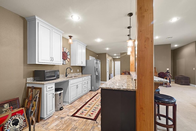 2741 Summit Dr, Joplin, MO 64804 - kitchen featuring stainless steel fridge with ice dispenser, a breakfast bar, white cabinetry, light stone counters, and recessed lighting
