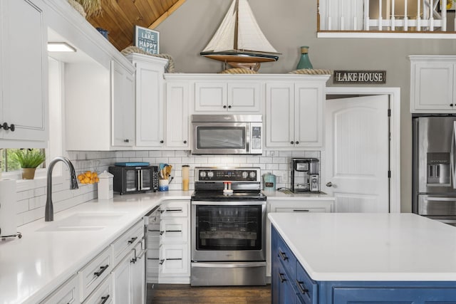 859 Crows Nest Trl, Branson, MO 65616 - kitchen featuring appliances with stainless steel finishes, blue cabinets, white cabinets, light countertops, and tasteful backsplash