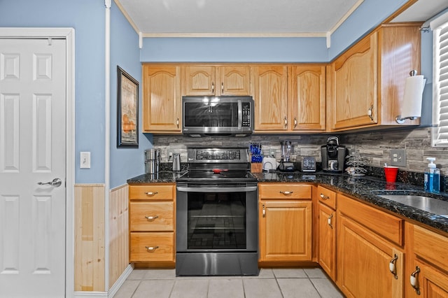 105 W Oak St, Nixa, MO 65714 - kitchen with appliances with stainless steel finishes, dark stone counters, light tile patterned floors, backsplash, and ornamental molding