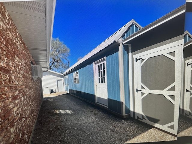 105 W Oak St, Nixa, MO 65714 - view of side of home featuring a metal roof, a wall mounted AC, and an outbuilding