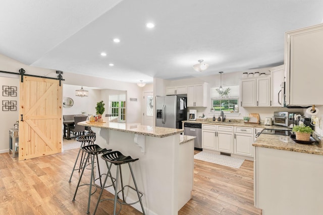 1865 Morningside Falls Blvd, Blue Eye, MO 65611 - kitchen with appliances with stainless steel finishes, a barn door, a center island, a breakfast bar, and light wood-style floors