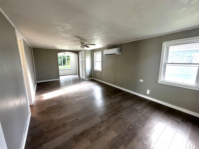 2609 W Lombard St, Springfield, MO 65802 - empty room featuring a wall unit AC, a ceiling fan, dark wood-style flooring, and arched walkways