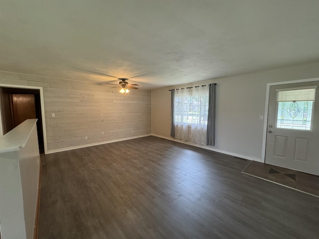 606 E Prairie Ln, Ash Grove, MO 65604 - unfurnished living room with wood walls, a ceiling fan, and dark wood finished floors