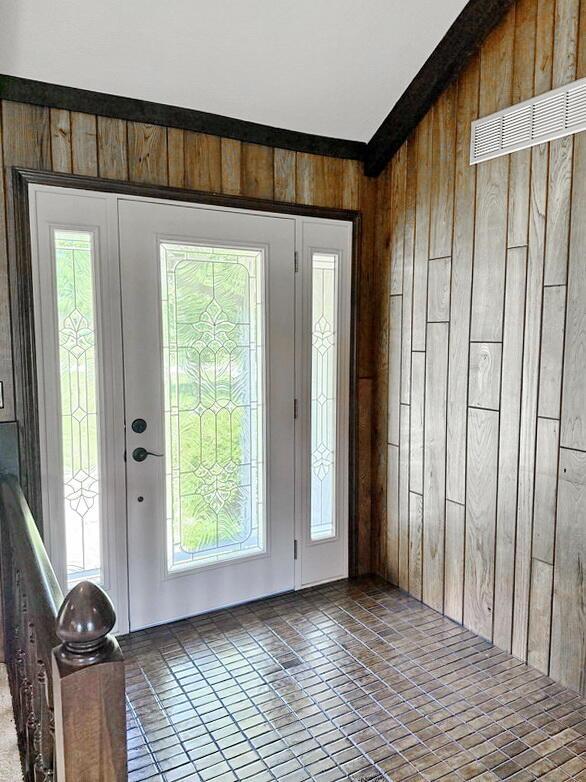 114 W Carman Rd, El Dorado Springs, MO 64744 - entrance foyer with wood walls, healthy amount of natural light, tile patterned flooring, and lofted ceiling