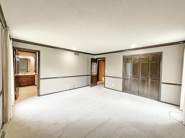 114 W Carman Rd, El Dorado Springs, MO 64744 - unfurnished bedroom with crown molding, light colored carpet, a closet, a textured ceiling, and ensuite bathroom
