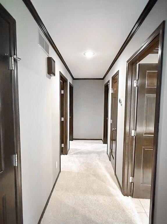 114 W Carman Rd, El Dorado Springs, MO 64744 - corridor featuring crown molding and light colored carpet