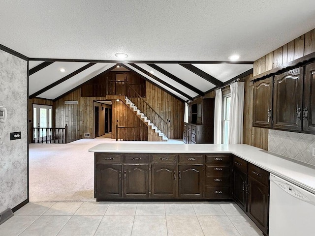 114 W Carman Rd, El Dorado Springs, MO 64744 - kitchen with dishwasher, light countertops, dark brown cabinets, wooden walls, and a textured ceiling