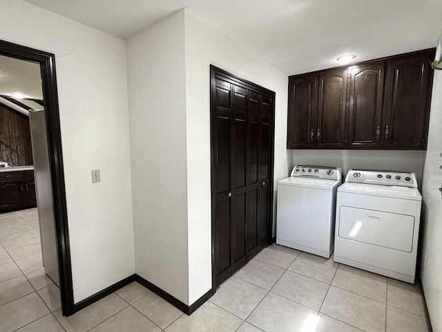 114 W Carman Rd, El Dorado Springs, MO 64744 - laundry room featuring washer and clothes dryer, light tile patterned flooring, and cabinet space