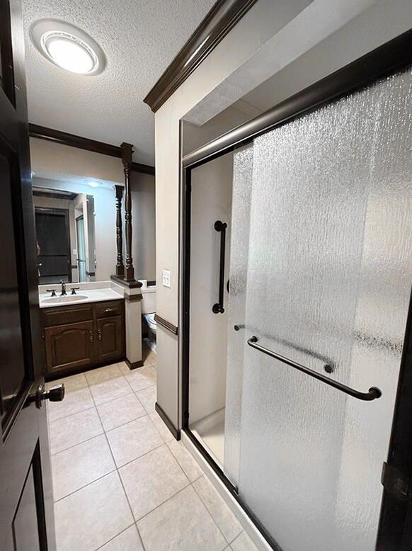114 W Carman Rd, El Dorado Springs, MO 64744 - bathroom with a shower stall, vanity, a textured ceiling, tile patterned flooring, and ornamental molding