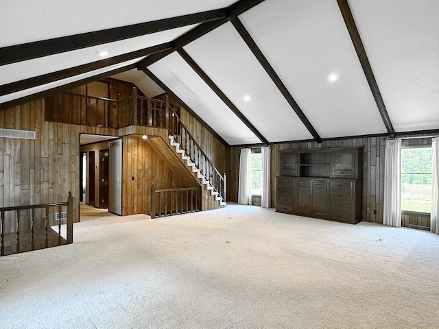114 W Carman Rd, El Dorado Springs, MO 64744 - unfurnished living room featuring wooden walls, beam ceiling, carpet flooring, and high vaulted ceiling