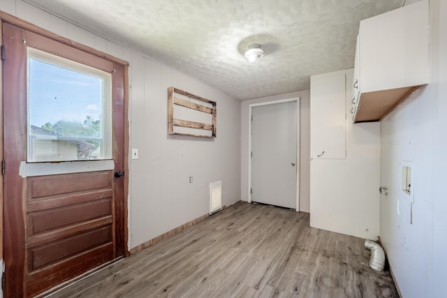 621 E Cleveland St, Seymour, MO 65746 - laundry area with light wood-style floors, a textured ceiling, and cabinet space