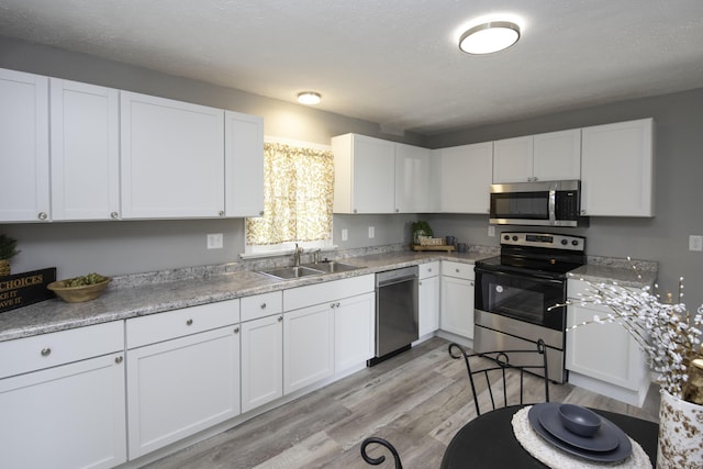 106 S 3rd Ave, Ozark, MO 65721 - kitchen featuring appliances with stainless steel finishes, white cabinets, light wood finished floors, and light countertops