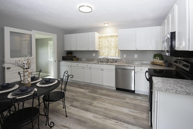 106 S 3rd Ave, Ozark, MO 65721 - kitchen with stainless steel appliances, white cabinets, light wood-type flooring, a textured ceiling, and light countertops