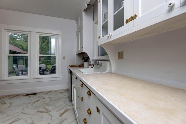 1510 E Mcdaniel St, Springfield, MO 65802 - kitchen with light countertops, light marble finish floors, glass insert cabinets, white cabinets, and stainless steel dishwasher