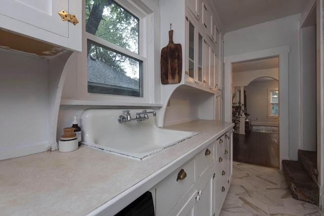 1510 E Mcdaniel St, Springfield, MO 65802 - kitchen with arched walkways, white cabinets, light countertops, glass insert cabinets, and light marble finish flooring