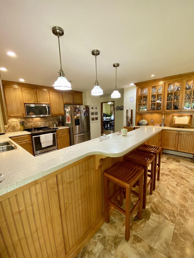 1605 S Park Ave, Aurora, MO 65605 - kitchen with appliances with stainless steel finishes, backsplash, brown cabinets, pendant lighting, and light stone counters