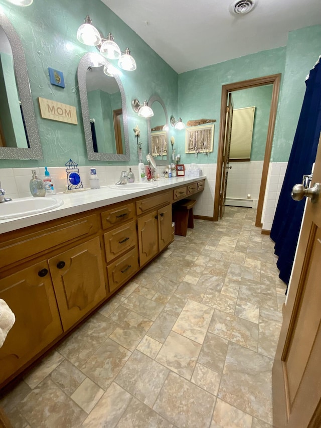 1605 S Park Ave, Aurora, MO 65605 - full bathroom featuring double vanity, stone finish flooring, a baseboard radiator, and tile walls