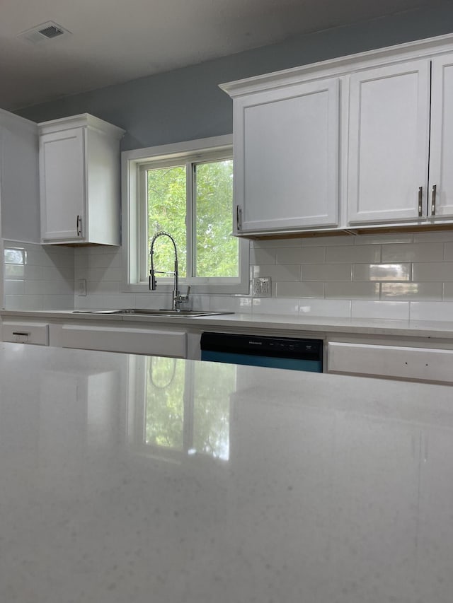 1506 6th St, Monett, MO 65708 - kitchen with tasteful backsplash, white cabinetry, light stone counters, and dishwasher