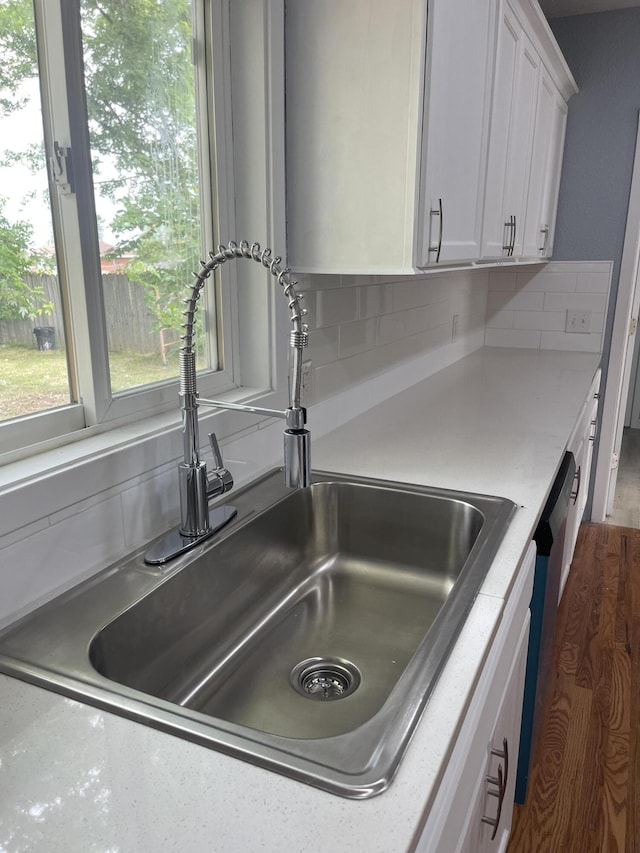 1506 6th St, Monett, MO 65708 - kitchen view of decorative backsplash, white cabinetry, light countertops, and stainless steel dishwasher