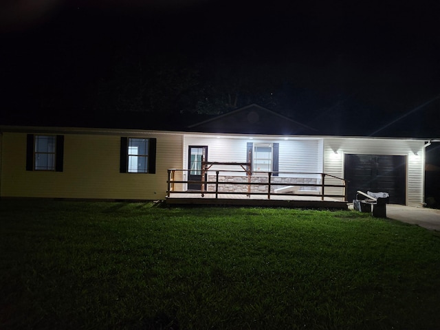 1506 6th St, Monett, MO 65708 - back of house at night featuring a garage and a lawn