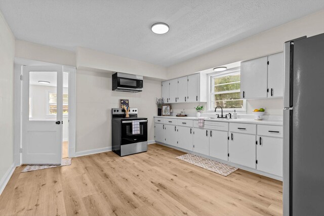 936 W Division St, Springfield, MO 65803 - kitchen featuring stainless steel electric range, freestanding refrigerator, light countertops, light wood-type flooring, and white cabinets