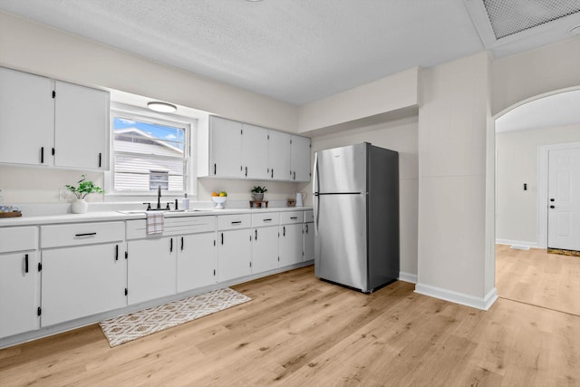 936 W Division St, Springfield, MO 65803 - kitchen with freestanding refrigerator, light wood-type flooring, arched walkways, light countertops, and white cabinets