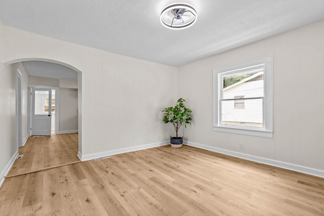 936 W Division St, Springfield, MO 65803 - empty room with arched walkways, wood finished floors, and a textured ceiling