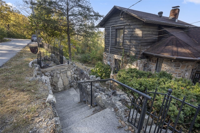 196 Lakeside Way, Forsyth, MO 65653 - view of home's exterior with a chimney, stone siding, stairs, and roof with shingles